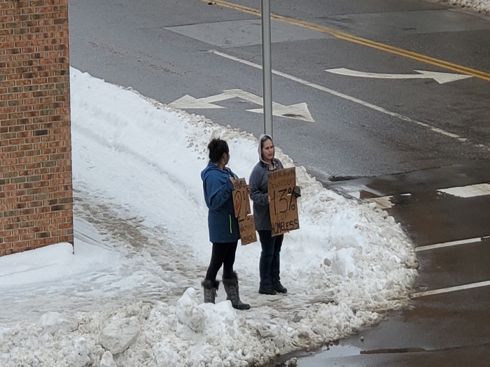 volunteers holding cardboard signs on street corner