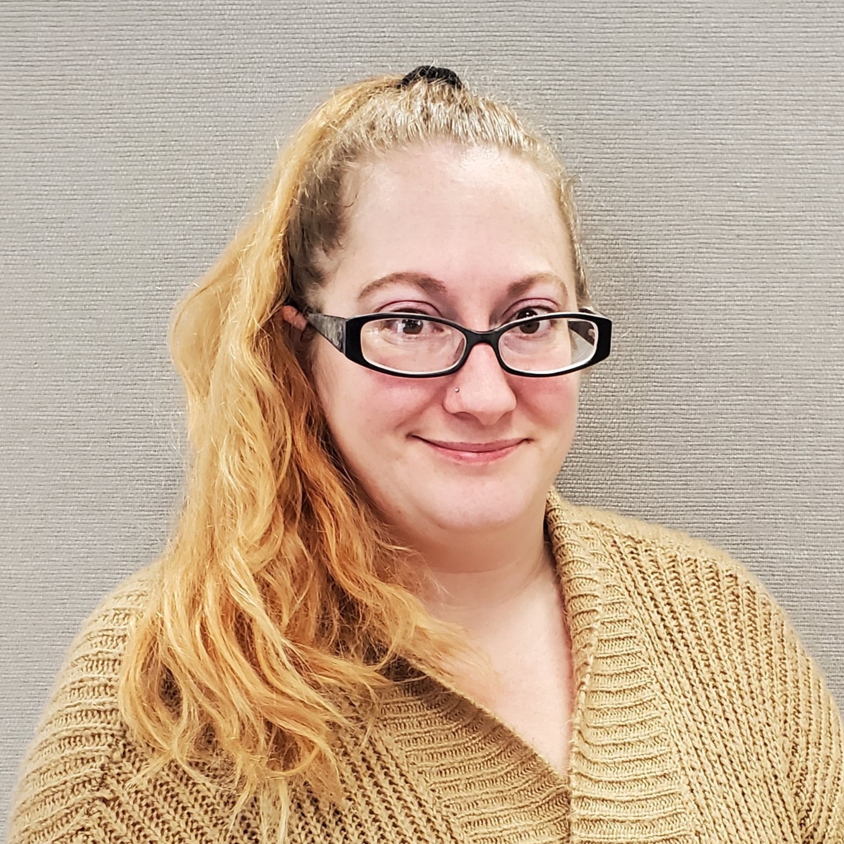 Woman with red blonde hair and glasses smiling