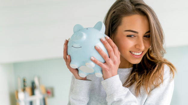 woman smiling and holding a piggy bank